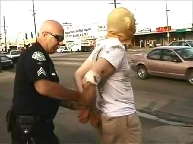 The masked man from the 'Thank You, Judge' music video is arrested by an LA cop.